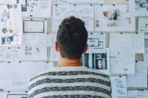 Back view of a man looking at a board full of papers and ideas, startup business owner planning how to get funding for his business as a non-Australian resident