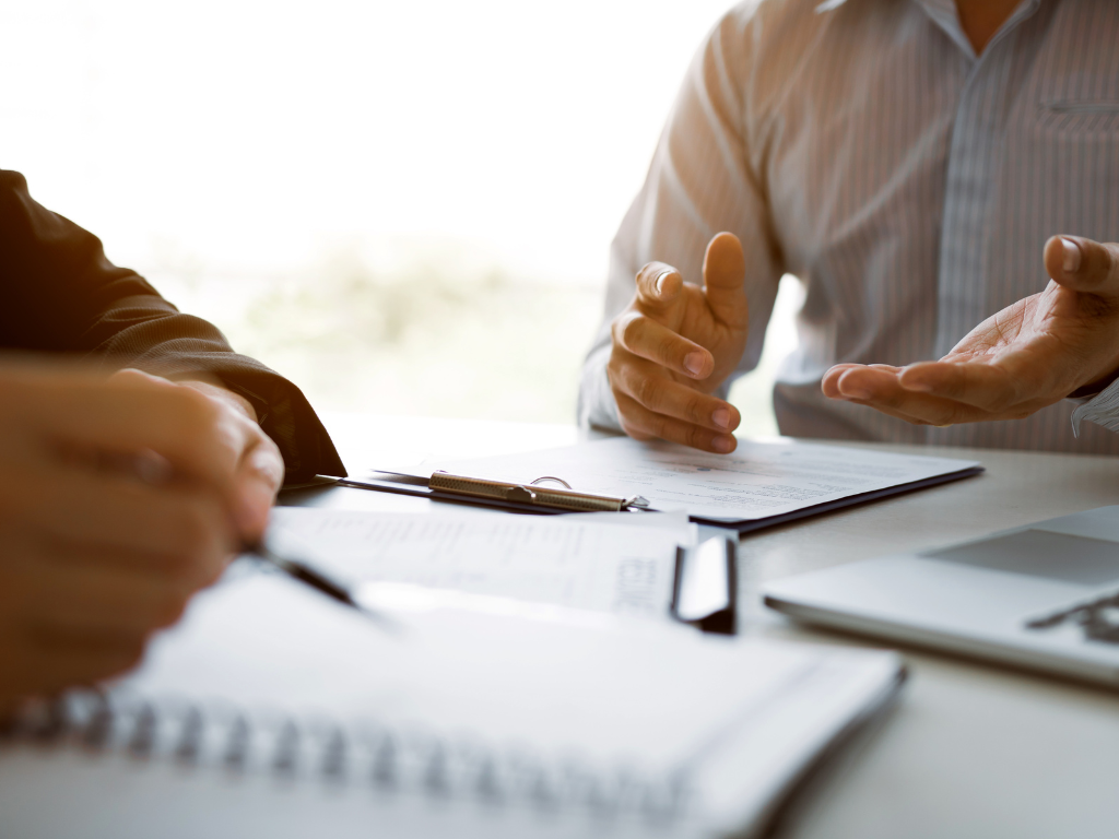 Zoomed and cropped photo of two people discussing documents, concept photo for a broker or lender discussing different commercial loan options for a borrower