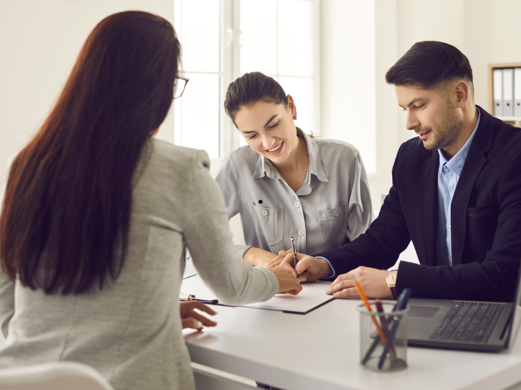 A business-owning couple signs a loan agreement after choosing the right type of commercial loan for their business.