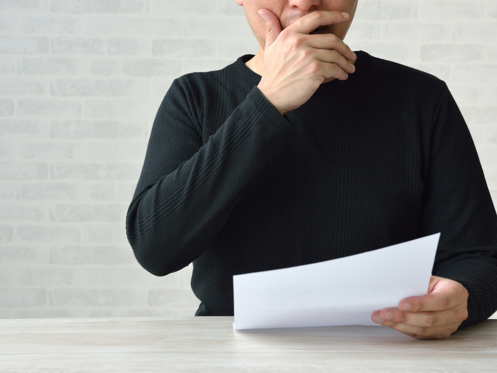 Zoomed and cropped photo of a man reading and considering the contents of a document, concept photo of a man reviewing the rates on his commercial loan