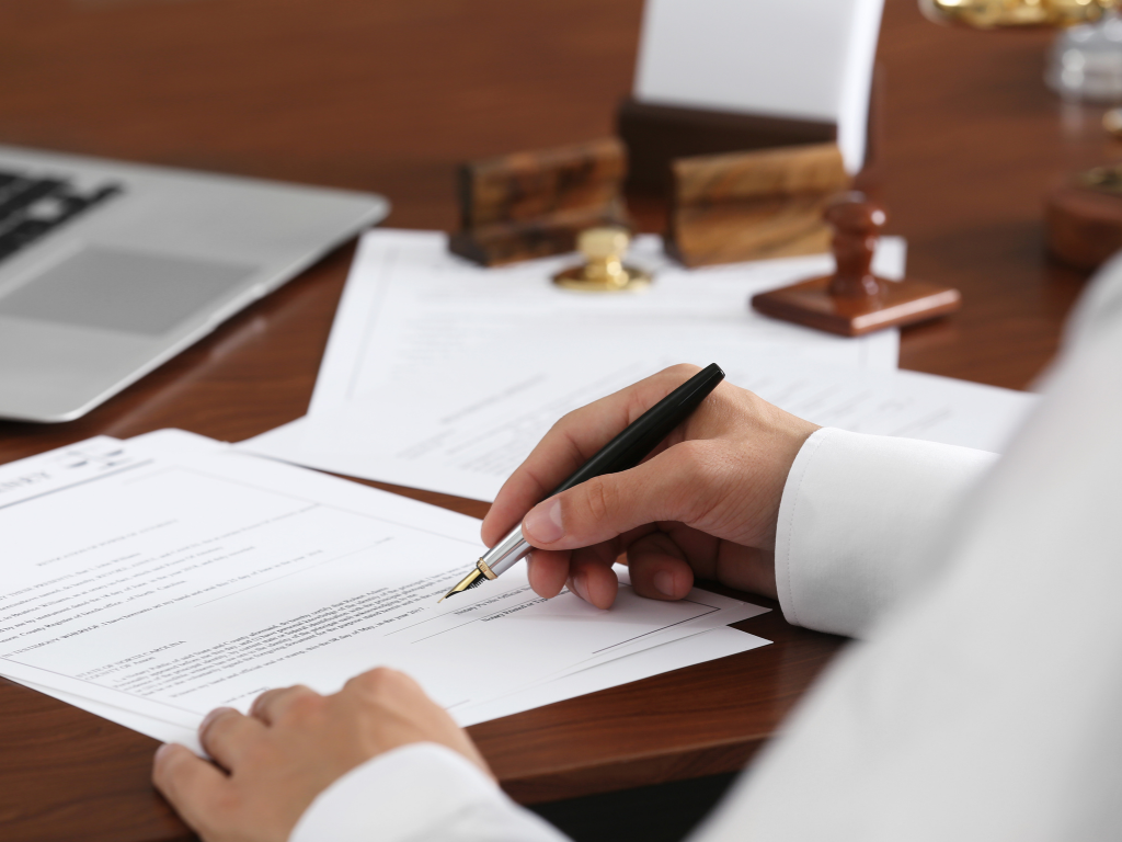 Zoomed and cropped photo of a man signing documents, concept photo of a business owner filing an application for a business line of credit