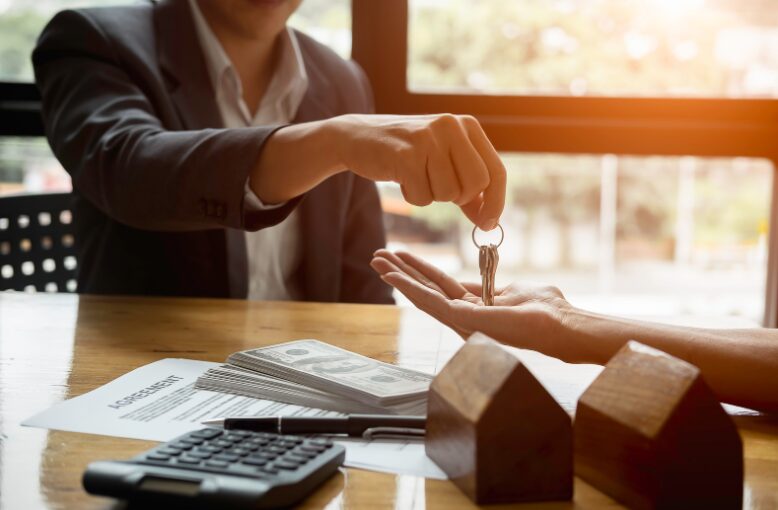 A close-up of a lender handing over house keys to a borrower, symbolising success in choosing the right second mortgage and securing the best second mortgage loans.