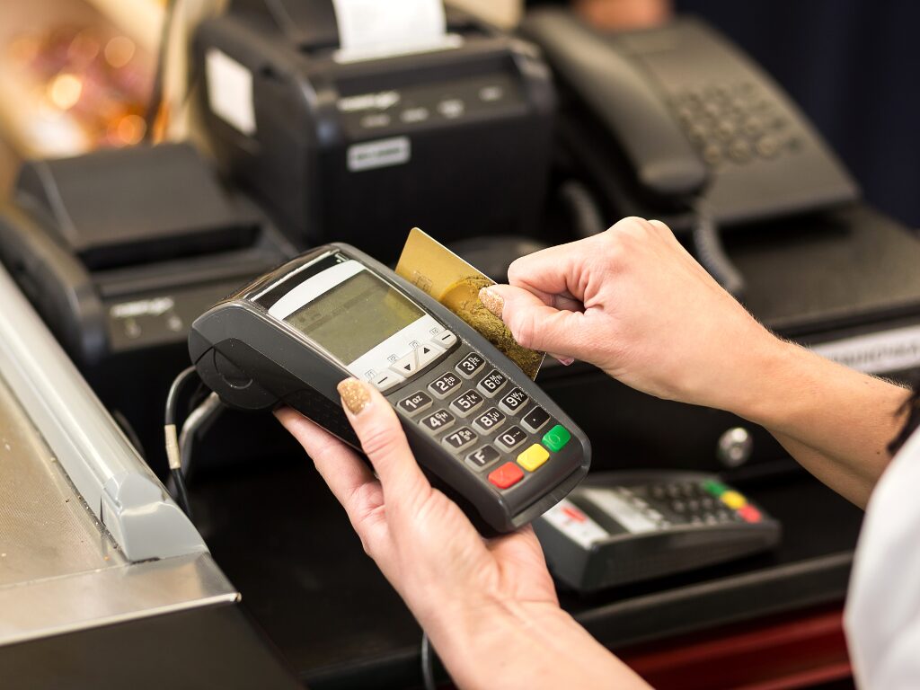 Zoomed in cropped photo of a woman using a credit card with a POS machine at a store