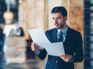 A man in a suit reviews documents, a business owner reviewing financials or credit report to see what business loan he qualifies for