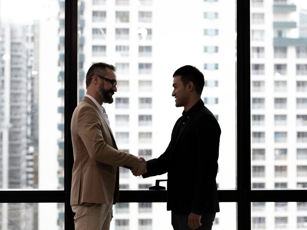 Two men in a business setting shake hands, concept photo for business owner and lender agree to terms for a business loan