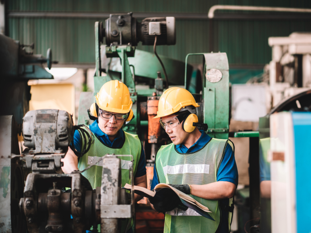 Two workers in high visibility vests and protective wear examine plant equipment, manufacturing equipment funded by equipment finance in Canberra