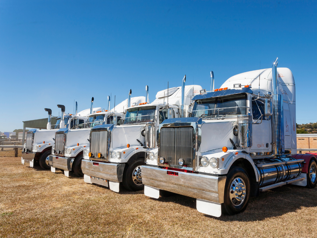 A row of 4 large freight trucks, a fleet of transport trucks funded by equipment finance