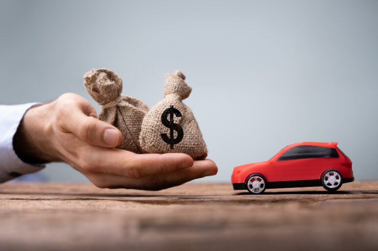 A hand holding a bag of dollars opposite a red car, representing the choice between an unsecured business overdraft vs secured business overdraft.