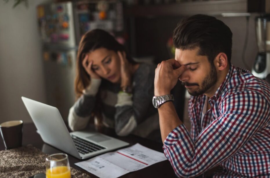 Worried couple stressed over tax debt, seeking ways to avoid tax debt loan scams and find legitimate financial solutions for relief.