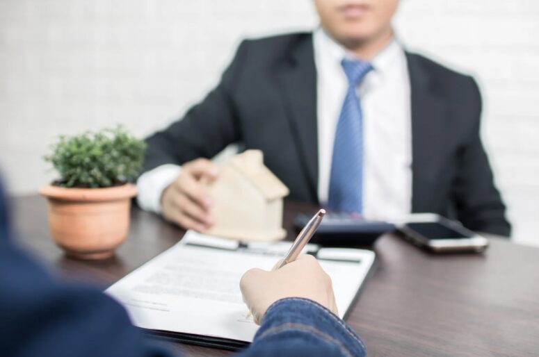 Financial broker explaining bank vs non-bank lenders for working capital financing to a business owner, with a pen signing a loan agreement.