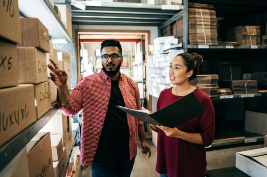 A male and female retail store owners in a warehouse discussing fitout financing for retailers and the best funding options for their shop.