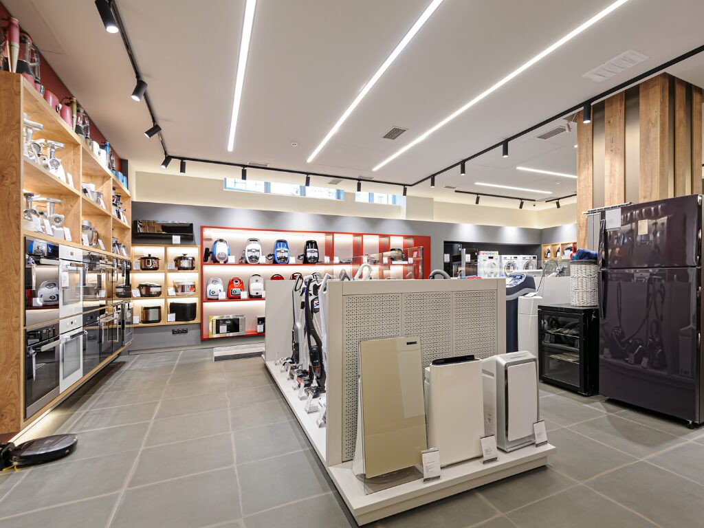 Beautiful and brightly-lit interiors of an appliance store with wooden finishes and white display areas, store renovated using fitout finance