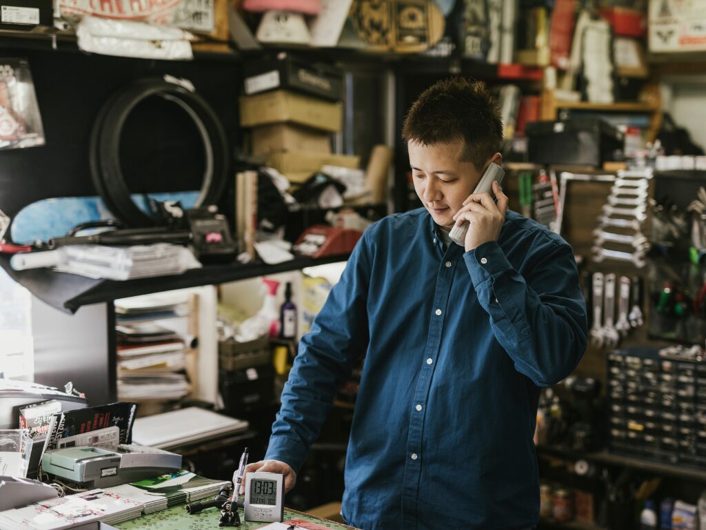 Business owner tending to his shop talking on the phone, business owner discussing a working capital funding solution with an expert