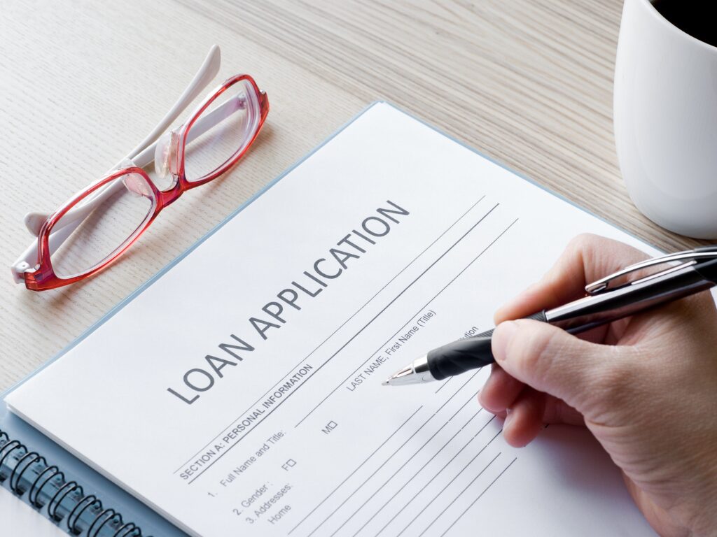 Cropped and zoomed photo of a hand filling up a loan application document, hand holding a pen and about to write on a documentCropped and zoomed photo of a hand filling up a loan application document, hand holding a pen and about to write on a document