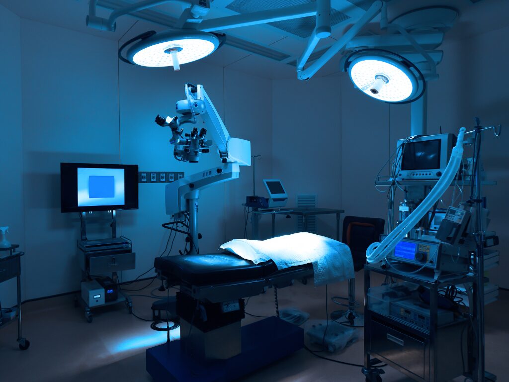 An empty operating room with bluish-white lighting, a fully equipped operating room with several machines funded with medical equipment finance