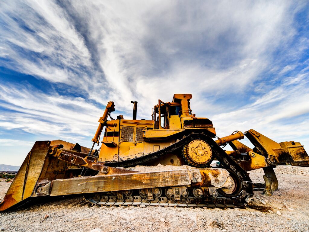 A weathered heavy equipment, large machinery for construction, yellow equipment set against a background of majestic clouds