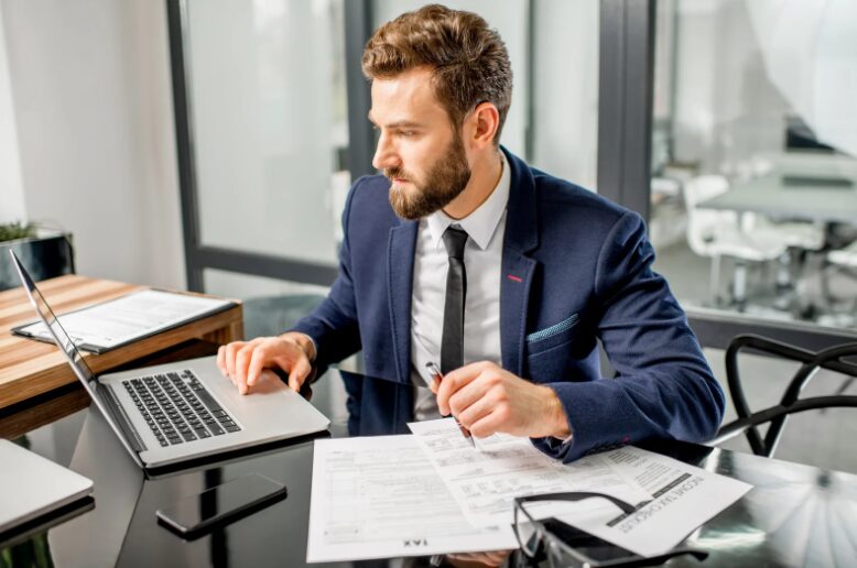 Tax manager reviewing equipment refinancing options in the office, assessing a business equipment loan for improved cash flow and tax benefits.