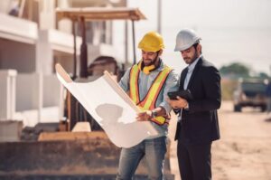 Civil engineer and construction worker discuss construction equipment financing options on-site, evaluating business equipment loans for the construction industry to fund heavy machinery.