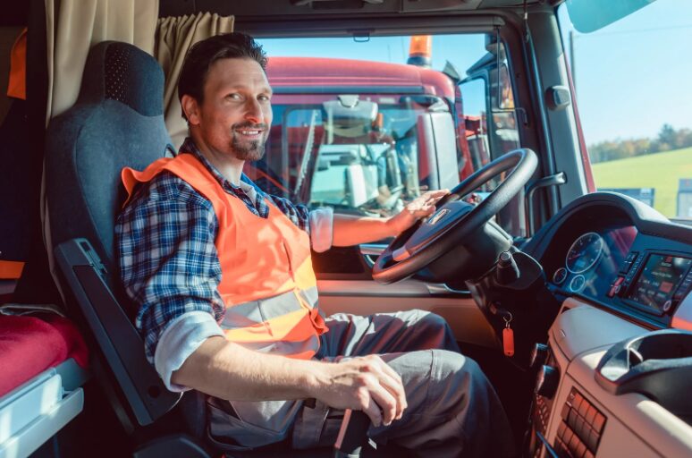 Truck driver sitting in the cabin, managing finances for a business truck loan, exploring transportation & truck financing options.