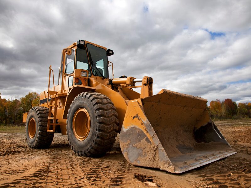 Large heavy equipment, Yellow industrial tractor driving over cracked dirt