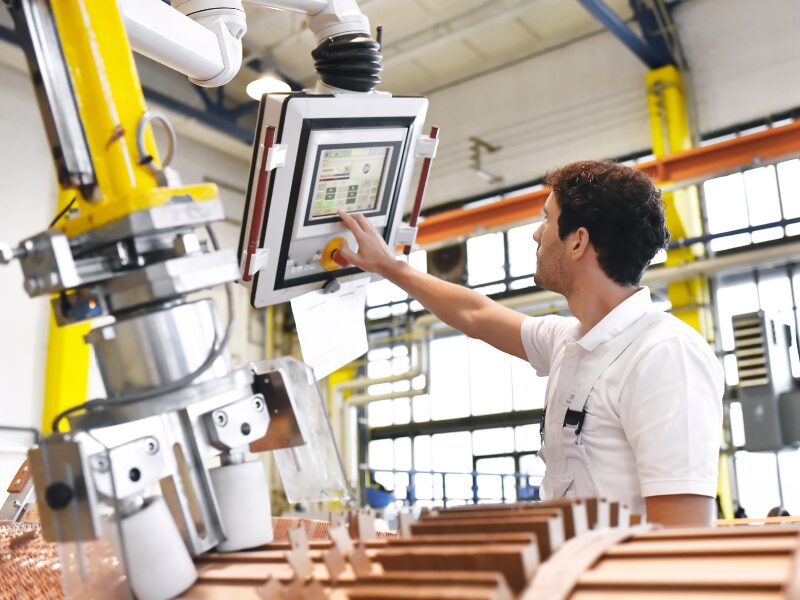 A factory worker operating the interface of a large manufacturing machine, manufacturing equipment