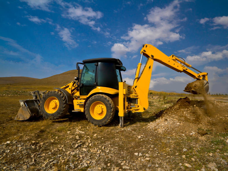 Small yellow excavator digging dirt