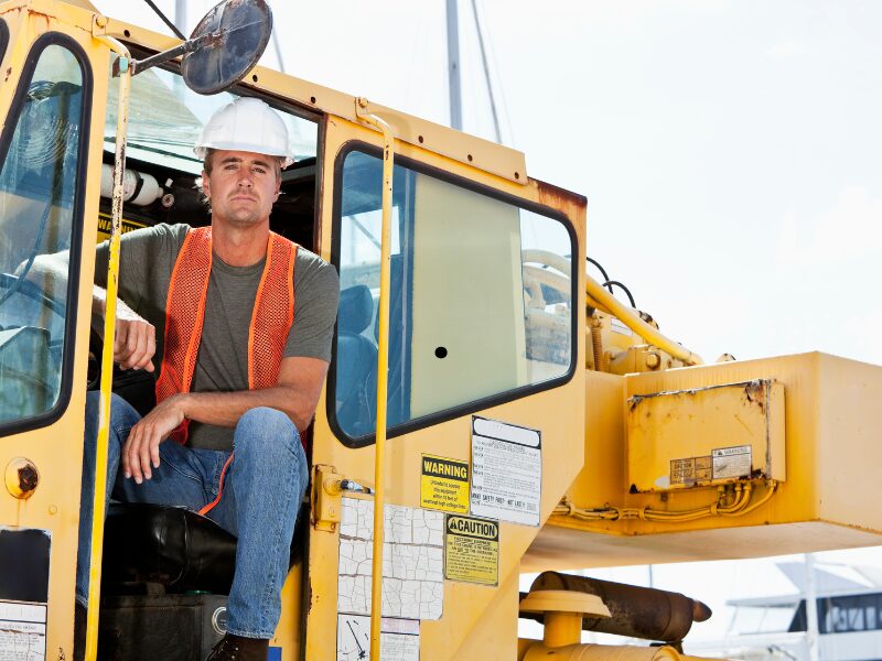 Heavy equipment operator sitting halfway out of his equipment with a serious look on his face