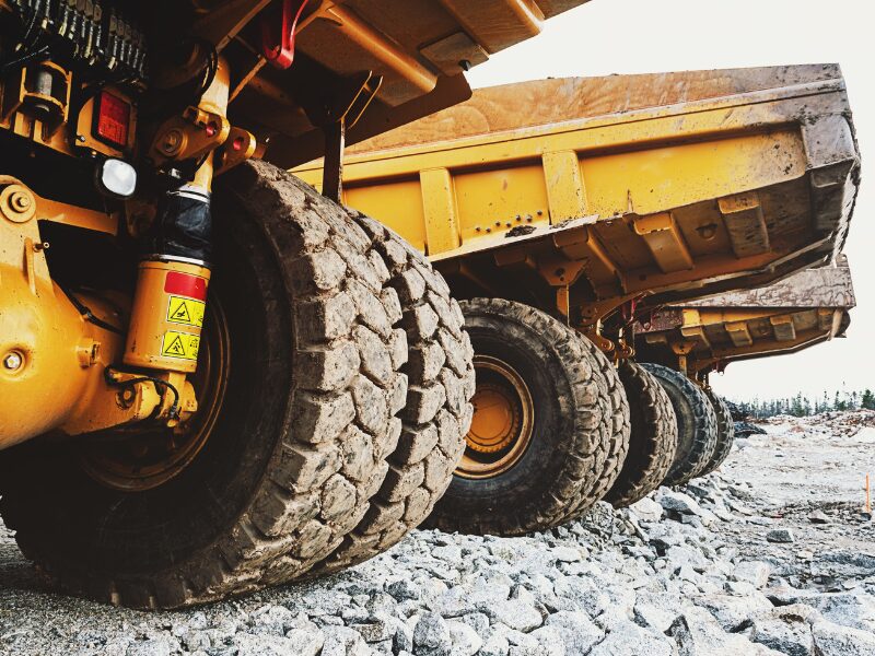 Artistic photo of a row of yellow heavy equipment, focusing on the weathered wheels of each machine