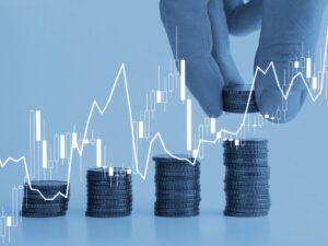 A hand piling coins into increasing order, with a blue overlay and graphics inspired by a rising line graph, a concept photo for making investments