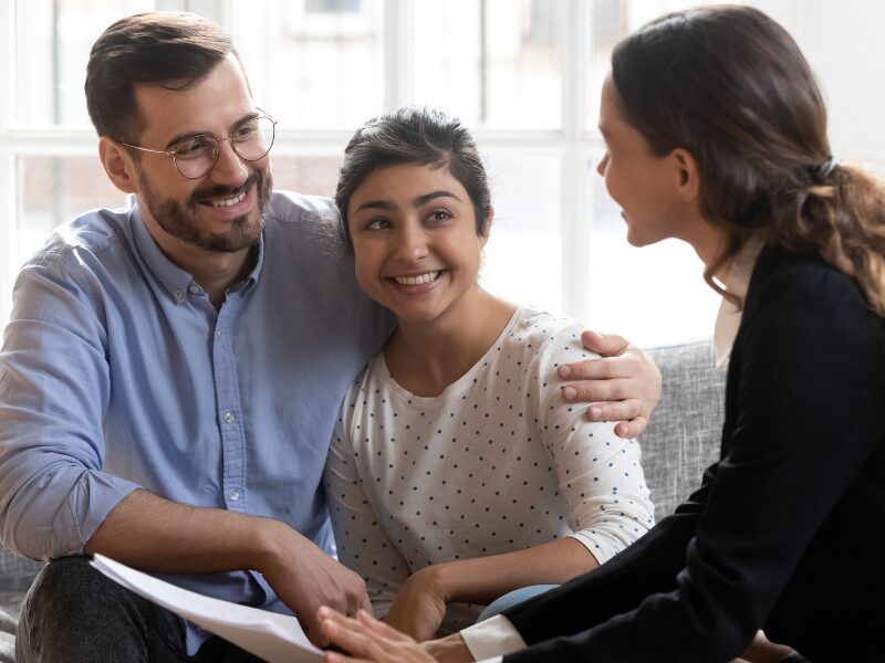 A business-owning couple happily discusses refinancing with a loan expert or a lender