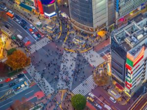Aerial view of Shibuya Crossing in Tokyo at dusk, showing organised pedestrian movement and vibrant city lights symbolising Japan’s urban structure and social order