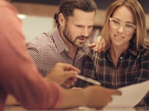 A lending expert or lender shows a couple the terms of a bad credit mortgage refinance solution