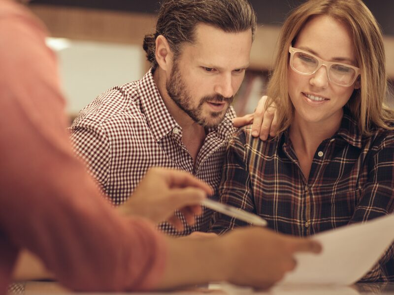 A lending expert or lender shows a couple the terms of a bad credit mortgage refinance solution