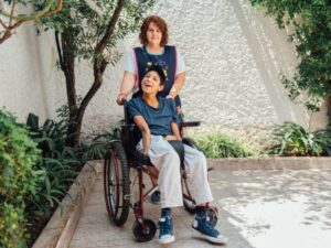 An NDIS provider pushing the wheelchair of a child with disability, disability support worker with a client