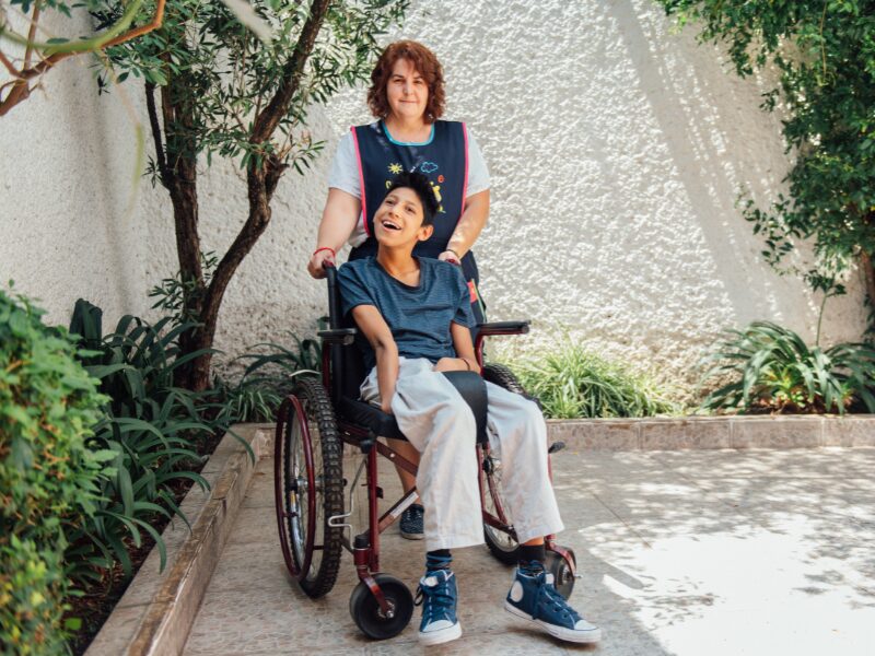 An NDIS provider pushing the wheelchair of a child with disability, disability support worker with a client