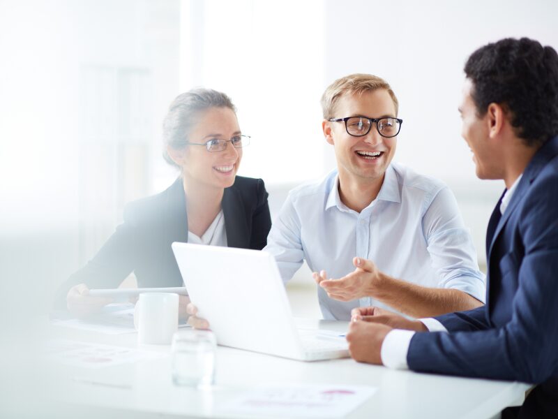 A man and a woman in a professional setting in a cheerful discussion with a man in a suit, borrowers discussing their loan choices with a broker or lender