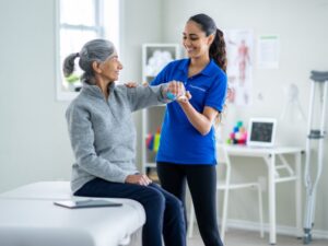 A physiotherapist smiles as she assists an NDIS participant during therapy