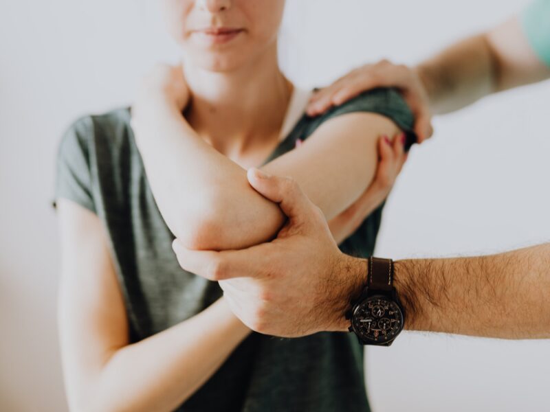 Cropped photo of a patient being assisted by a physiotherapist during arm stretches