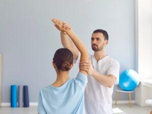 A physiotherapist assists a client with arm stretches