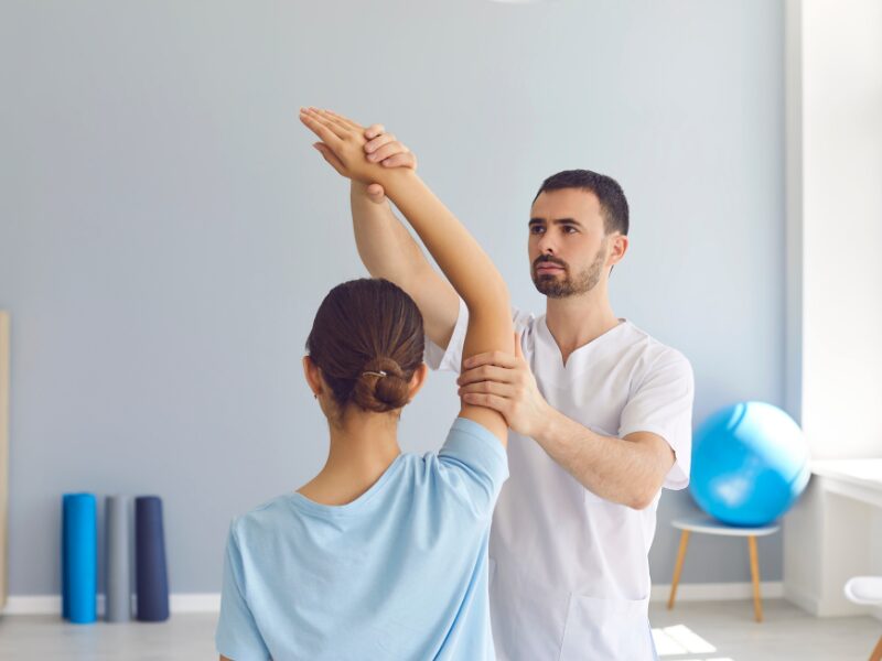 A physiotherapist assists a client with arm stretches