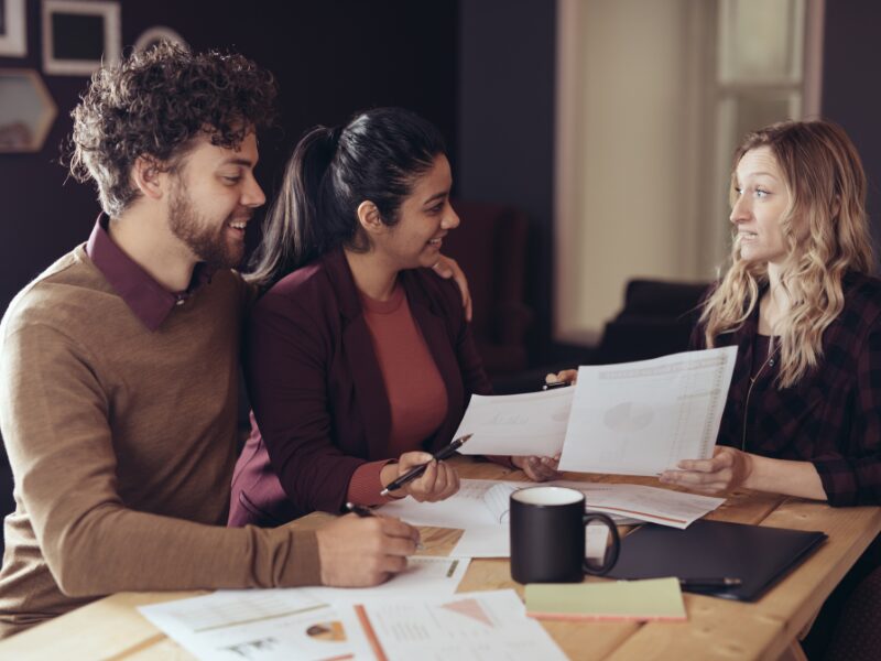 A couple discusses documents with a lending expert or lender, discussing what type of tax debt loan to choose