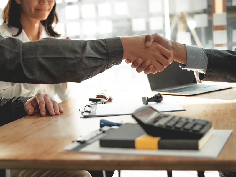 A business owner shakes hands with a mortgage broker or lender, agreeing on a loan solution for tax debt