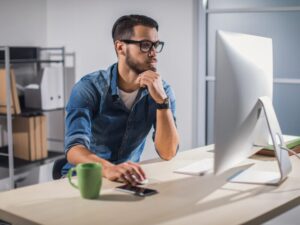 A man with his hand on his chin uses his computer, weighing home loan options with mortgage offset account features