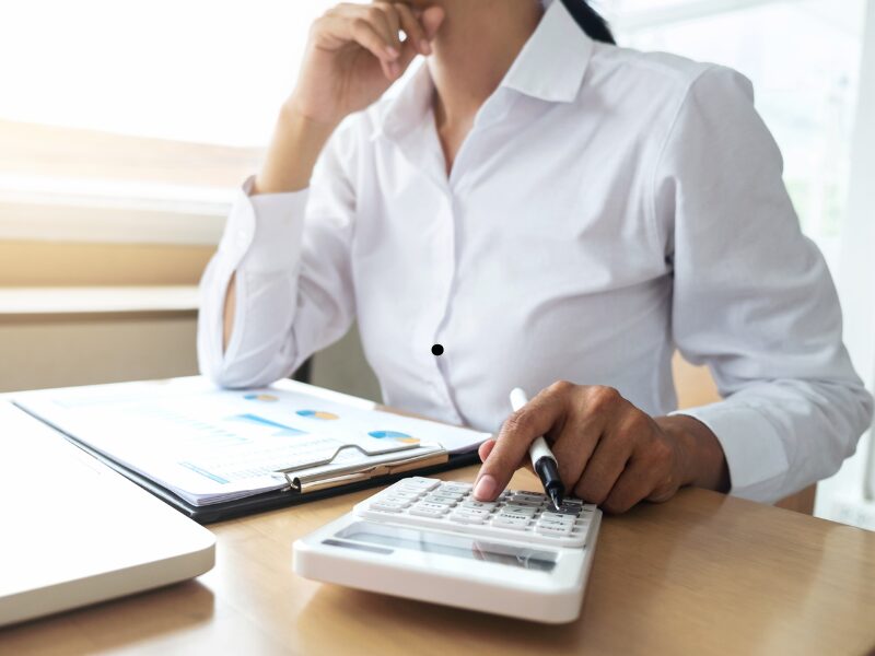 A woman with her hand on her chin uses a calculator, a home owner calculating interest savings for an offset account