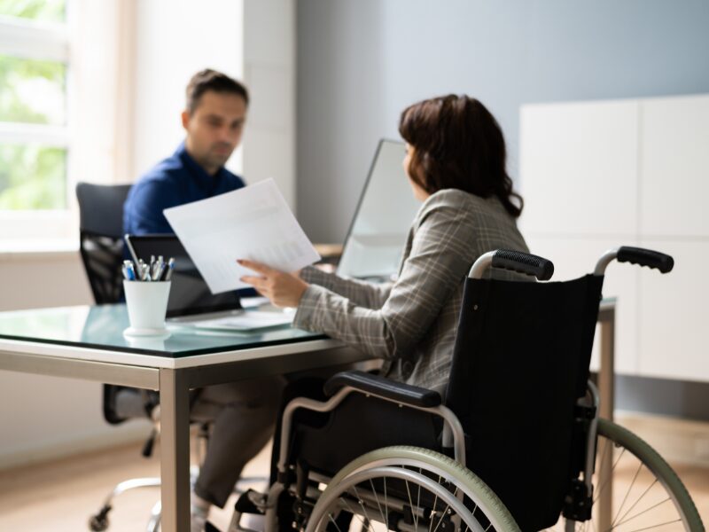 An NDIS participant in a wheelchair meets with an allied health worker, discussing healthcare plans