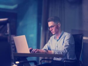 A man in glasses concentrates as he types on his laptop, a business owner preparing for tax deductibility changes