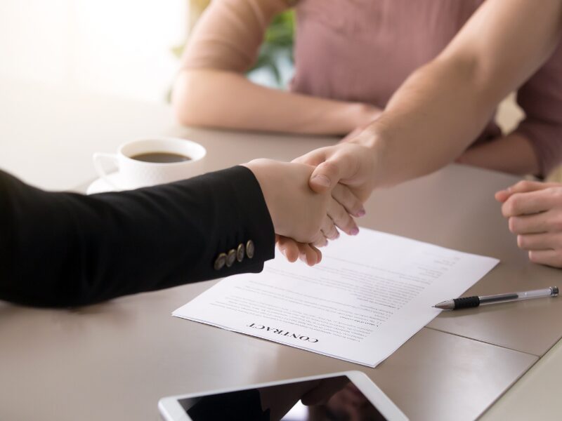 A lender or mortgage broker shakes hands with a business owner after signing a tax debt loan contract