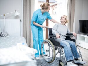 A disability support worker happily talks to an elderly woman in a wheelchair