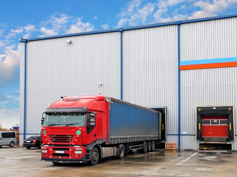 A red freight truck getting loaded at a warehouse