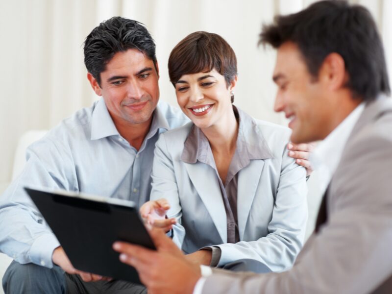 A financial planner shows a document to a happy couple during a consultation meeting